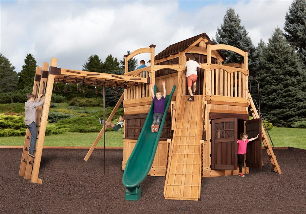 Titan Treehouse XL 14 swing set with green slide, climbing wall, and wooden clubhouse.